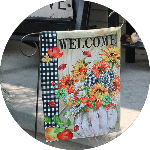 A welcome flag with a white pumpkin and several fall flowers.